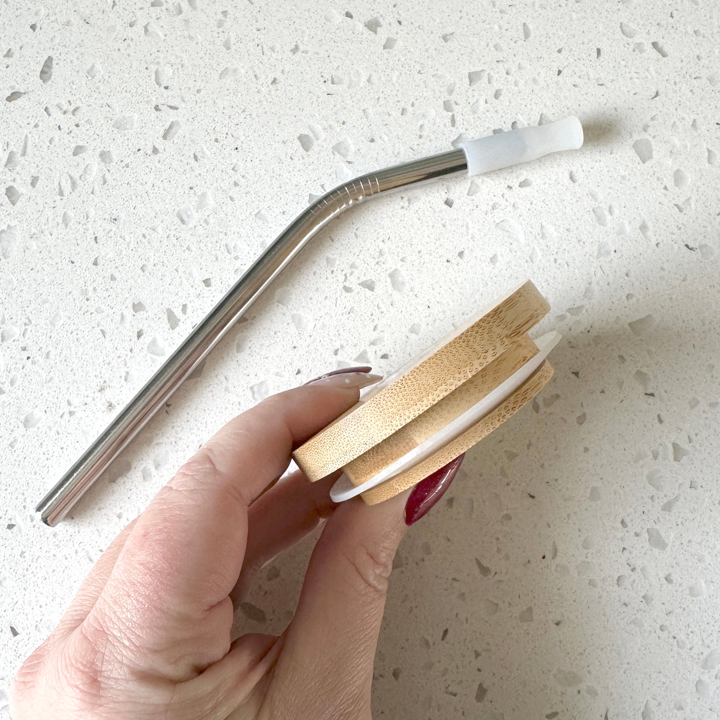 Hand holding bamboo lid and stainless steel straw, demonstrating the eco-friendly design by Counter Couture.