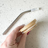 Hand holding bamboo lid and stainless steel straw, demonstrating the eco-friendly design by Counter Couture.