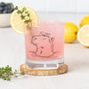 Capybara Rocks Glass filled with a pink beverage, garnished with lemon and herb, emphasizing the detailed capybara design.