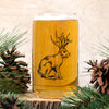 Jackalope Beer Can Glass by Counter Couture filled with beer, showcasing hand-drawn illustration of a jackalope, surrounded by pine branches and pine cones.