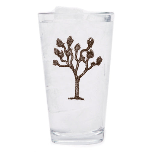 The stylish Joshua Tree Pint Glass, perfect for craft beer enthusiasts, sitting on a wooden table.