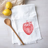 Stylish strawberry flour sack towel laid out with wooden spoon and fresh lemons, perfect for kitchen décor and functionality.