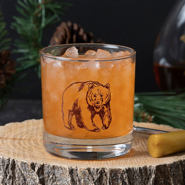 Bear whiskey glass filled with an orange drink and ice.