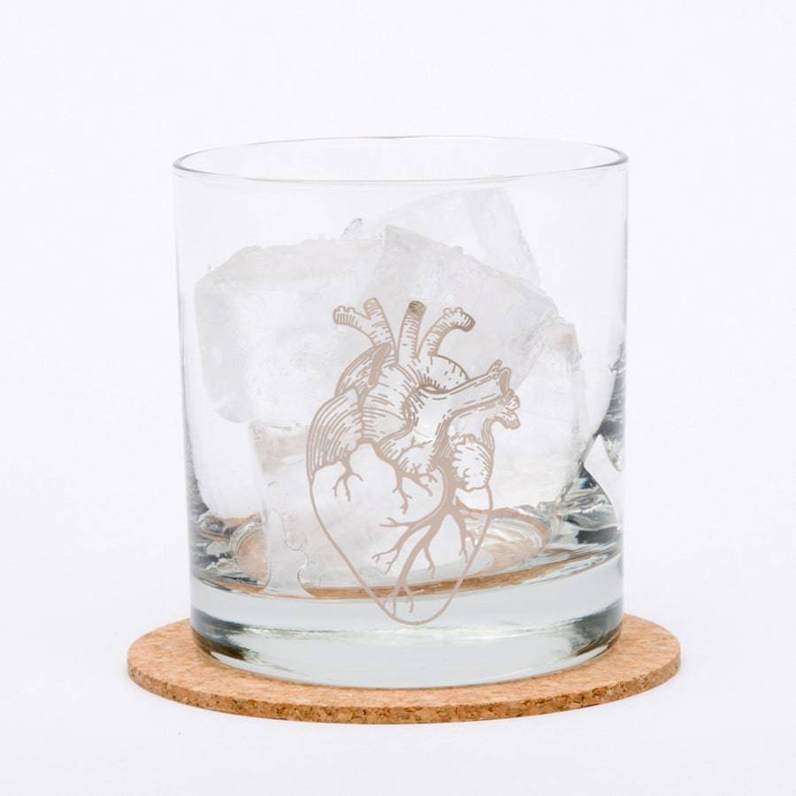 Anatomical Heart Rocks glass sitting on a coaster, filled with ice on white background.
