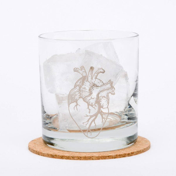 Anatomical Heart Rocks glass sitting on a coaster, filled with ice on white background.