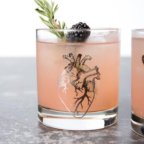 Whiskey glass printed with a silver anatomical heart, filled with a pink drink