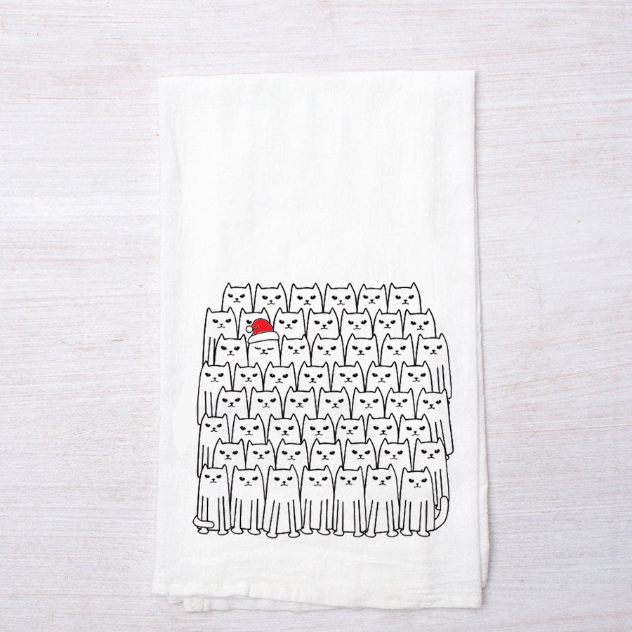 Counter Couture Santa Cats flour sack towel lying flat, showcasing a fun pattern of cats, with one cat prominently wearing a red Santa hat.