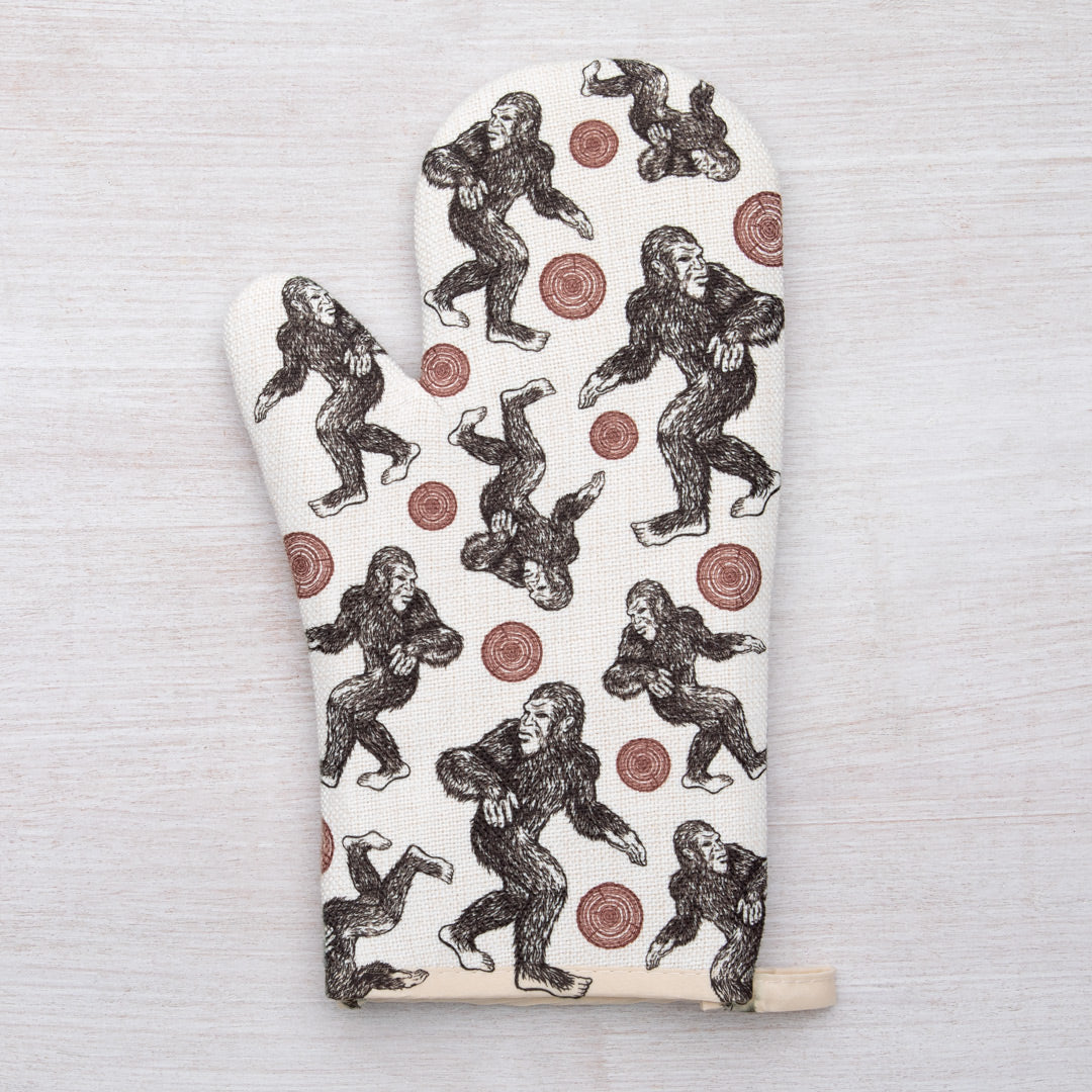 Stylish Sasquatch Oven Mitt displayed with kitchen utensils, highlighting its fun and functional design.