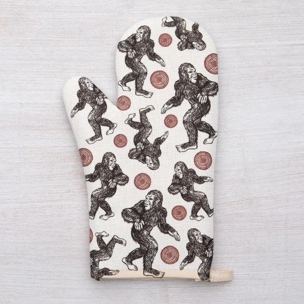 Stylish Sasquatch Oven Mitt displayed with kitchen utensils, highlighting its fun and functional design.