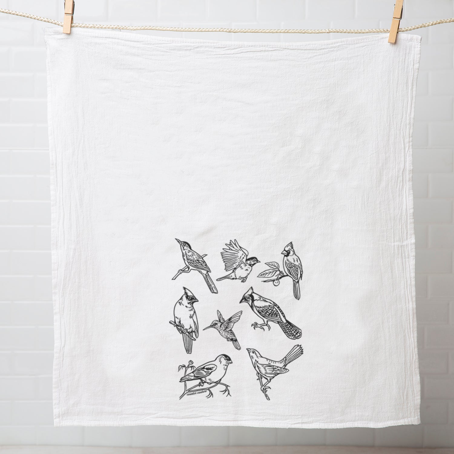 a tea towel with a bird design hanging on a clothes line