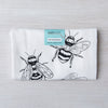 Folded Bumble Bee flour sack tea towel displaying intricate bee designs, with a tag indicating it is made of 100% cotton and printed in Colorado.