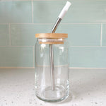 Clear glass can with bamboo lid and metal straw on kitchen counter