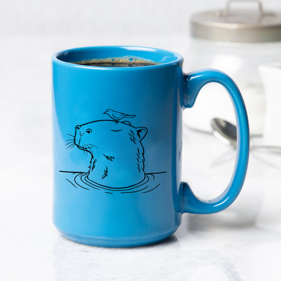 Blue ceramic mug with black line art of a capybara in water and a bird on its head