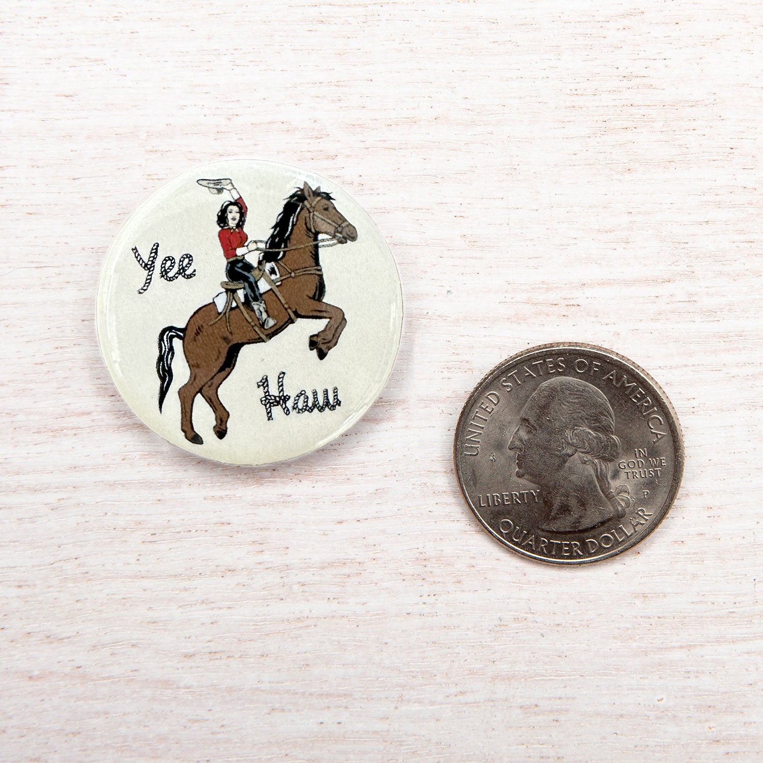 Cowgirl button pin with Yee Haw text and rodeo horse illustration next to a US quarter