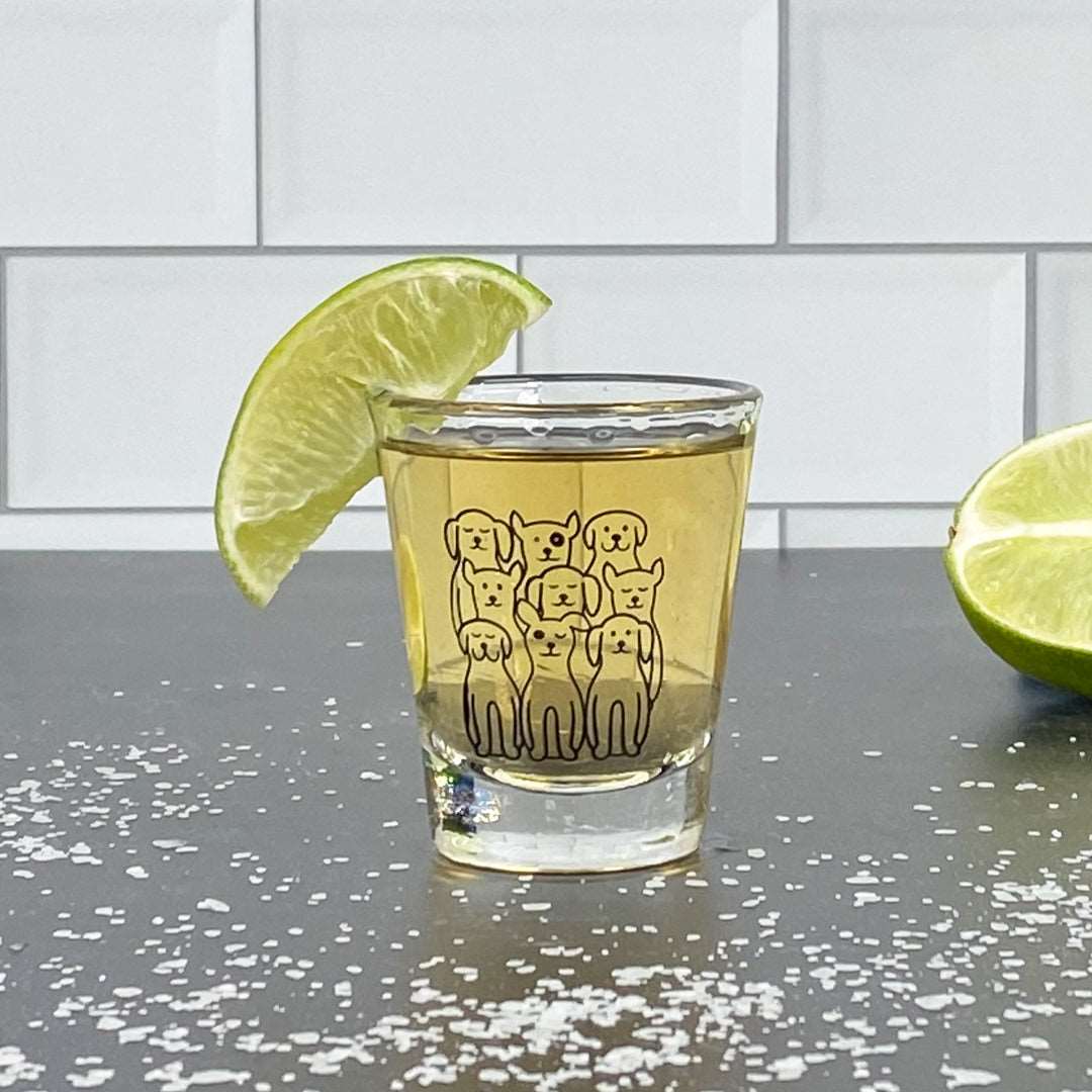 Dog-themed shot glass filled with liquor, garnished with lime, on a salt-sprinkled counter.