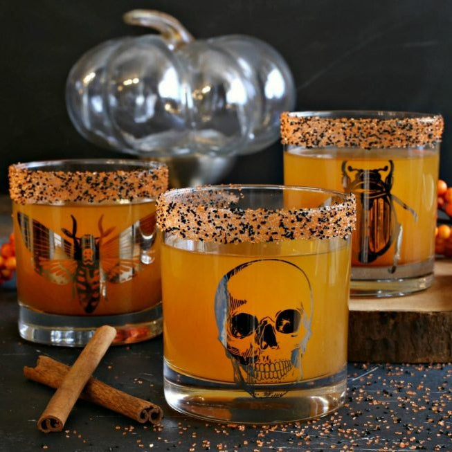 Chic Macabre Rocks Glass Set showcasing skull design, perfect for cocktails, featuring intricately detailed illustrations in platinum silver ink.