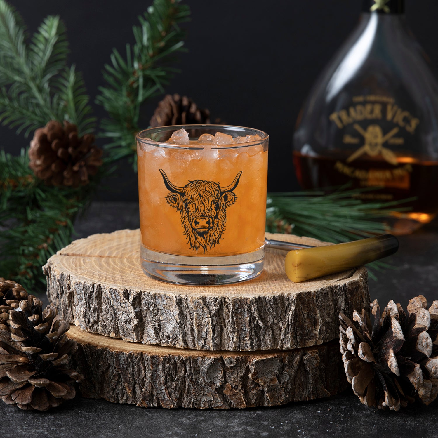 Highland cow whiskey glass filled with ice and a cocktail, elegantly displayed on a rustic wooden background.