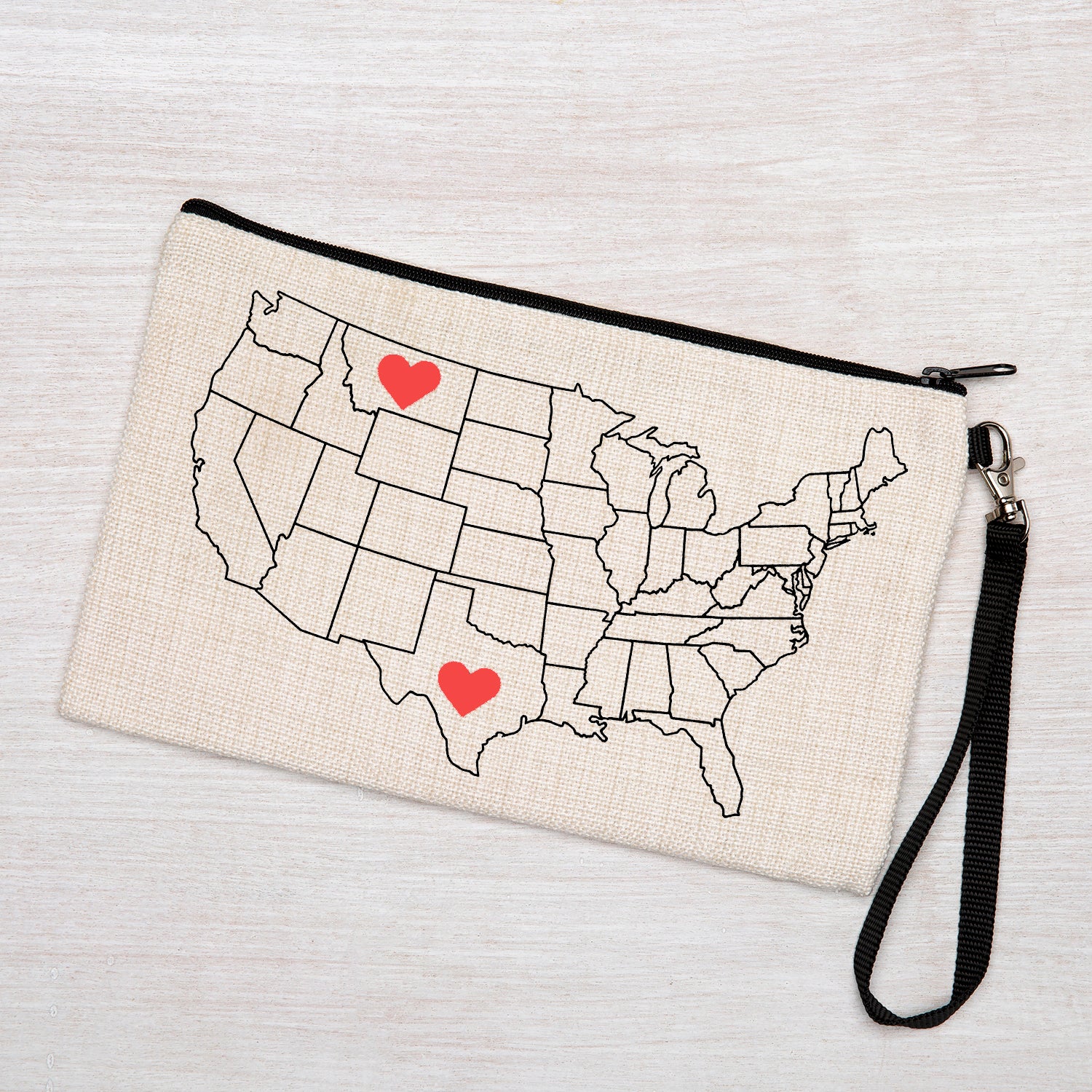 Canvas wristlet pouch with USA map outline and two red hearts, zipper bag on light wood surface