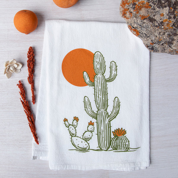 a towel with a cactus on it next to two oranges