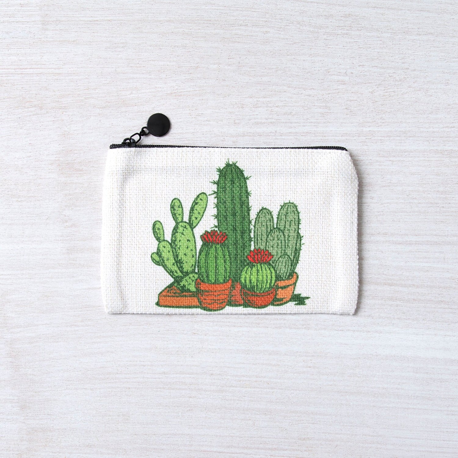 White zipper pouch with hand-drawn cactus and succulent illustration on a light background