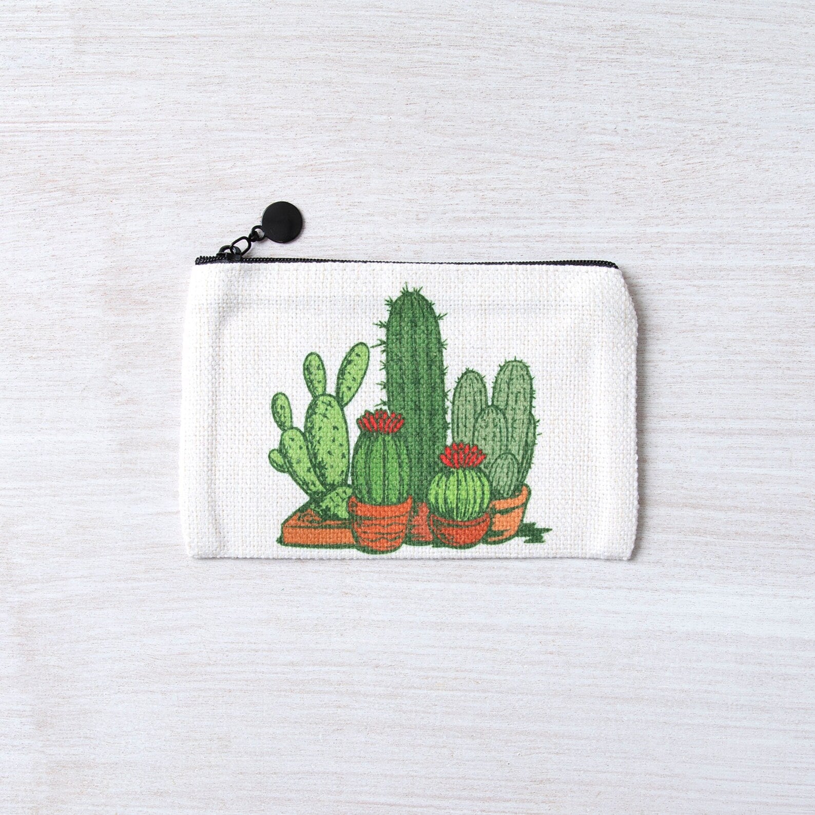 White zipper pouch with hand-drawn cactus and succulent illustration on a light background