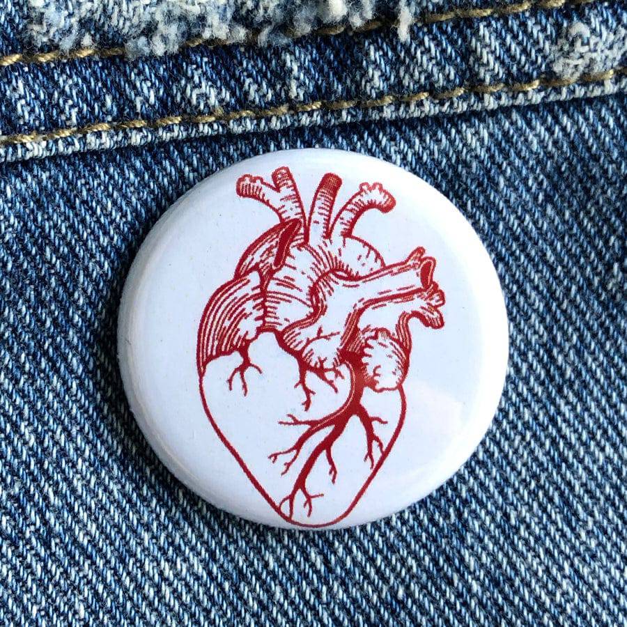 Anatomical heart illustration button pin on blue denim fabric