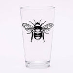 Clear pint glass with detailed black bee illustration on white background
