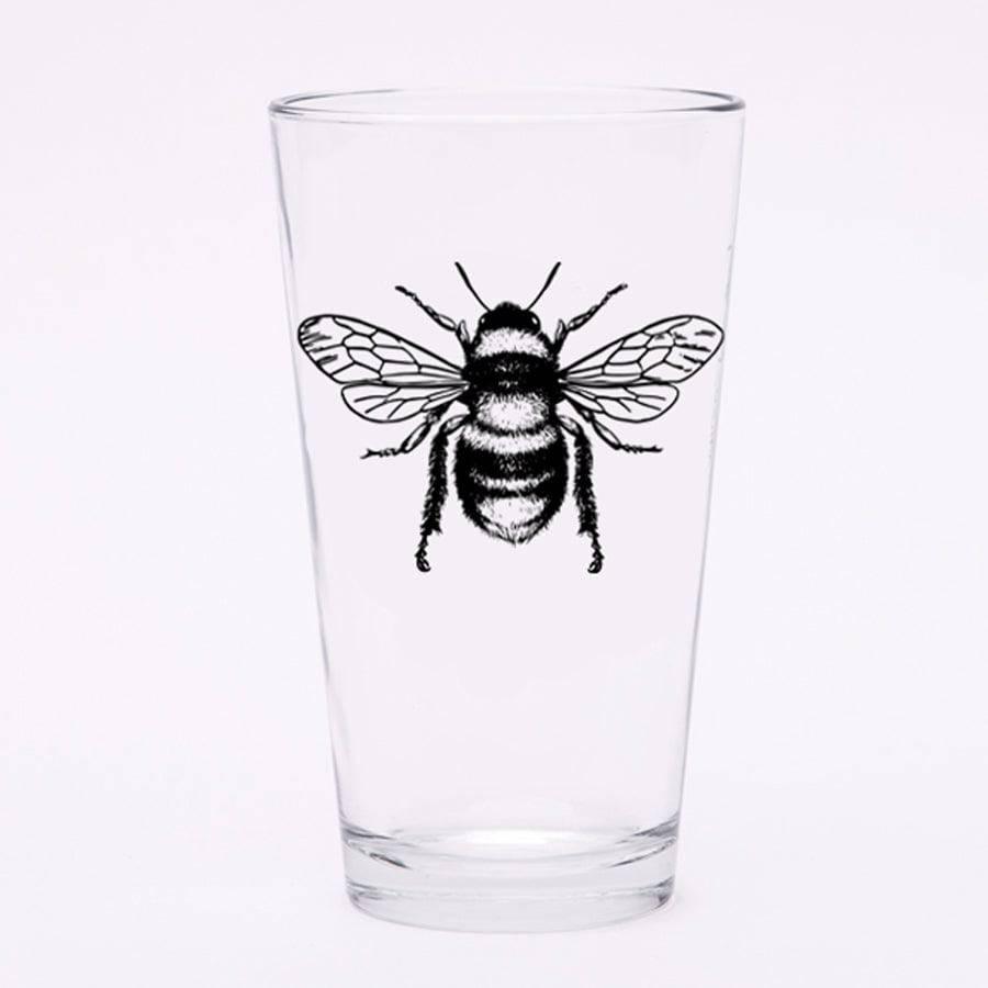 Clear pint glass with detailed black bee illustration on white background