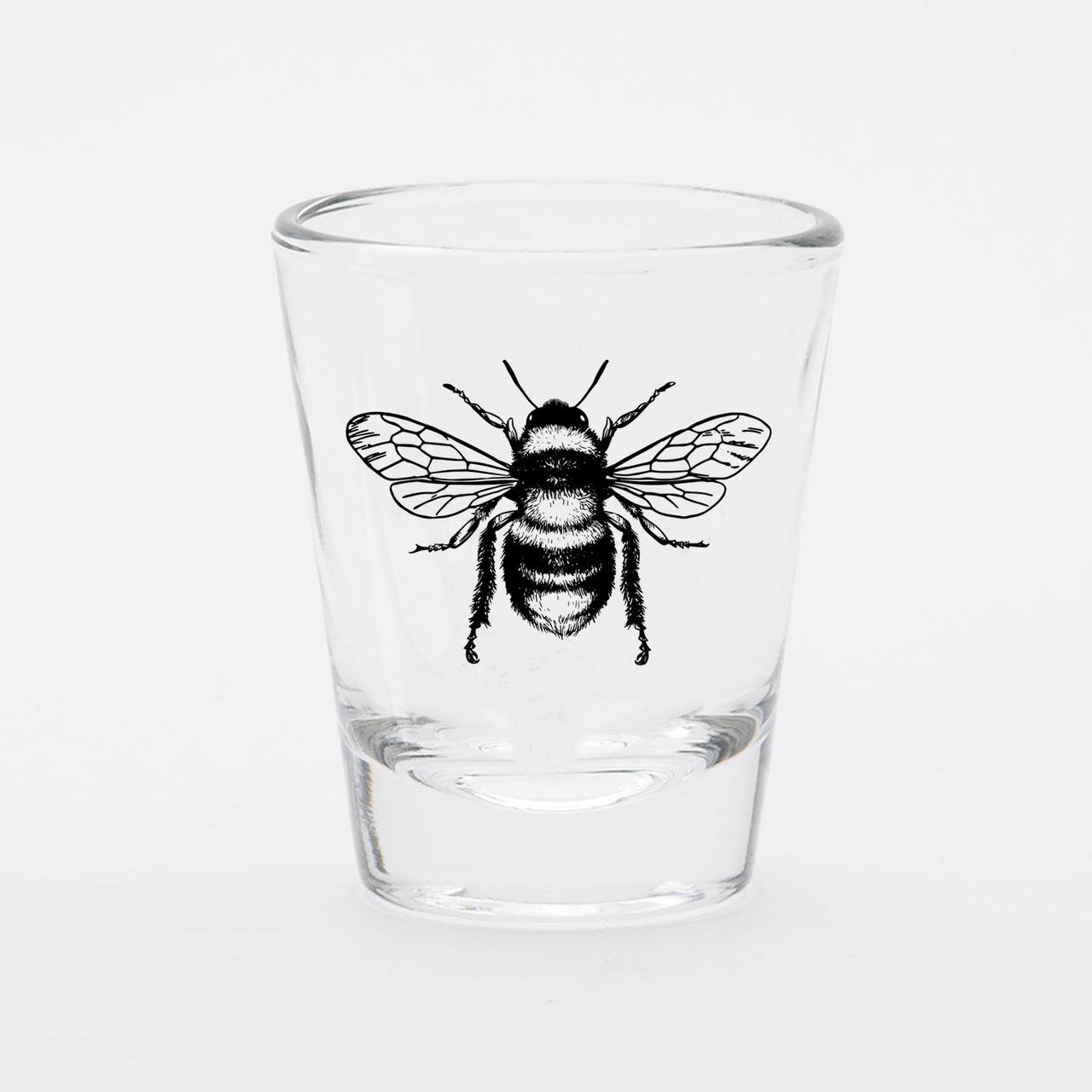 Clear shot glass with a detailed black bee illustration on the front