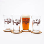 Set of four pint glasses with bison graphic, one filled with beer, on cork coasters