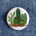 Round cactus button with colorful potted cactus illustration on denim fabric background