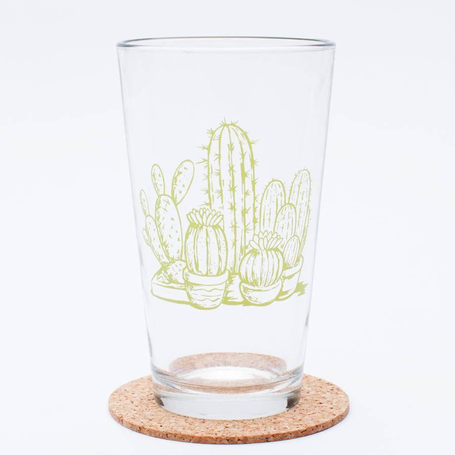 Clear pint glass with green cactus illustration, placed on a cork coaster