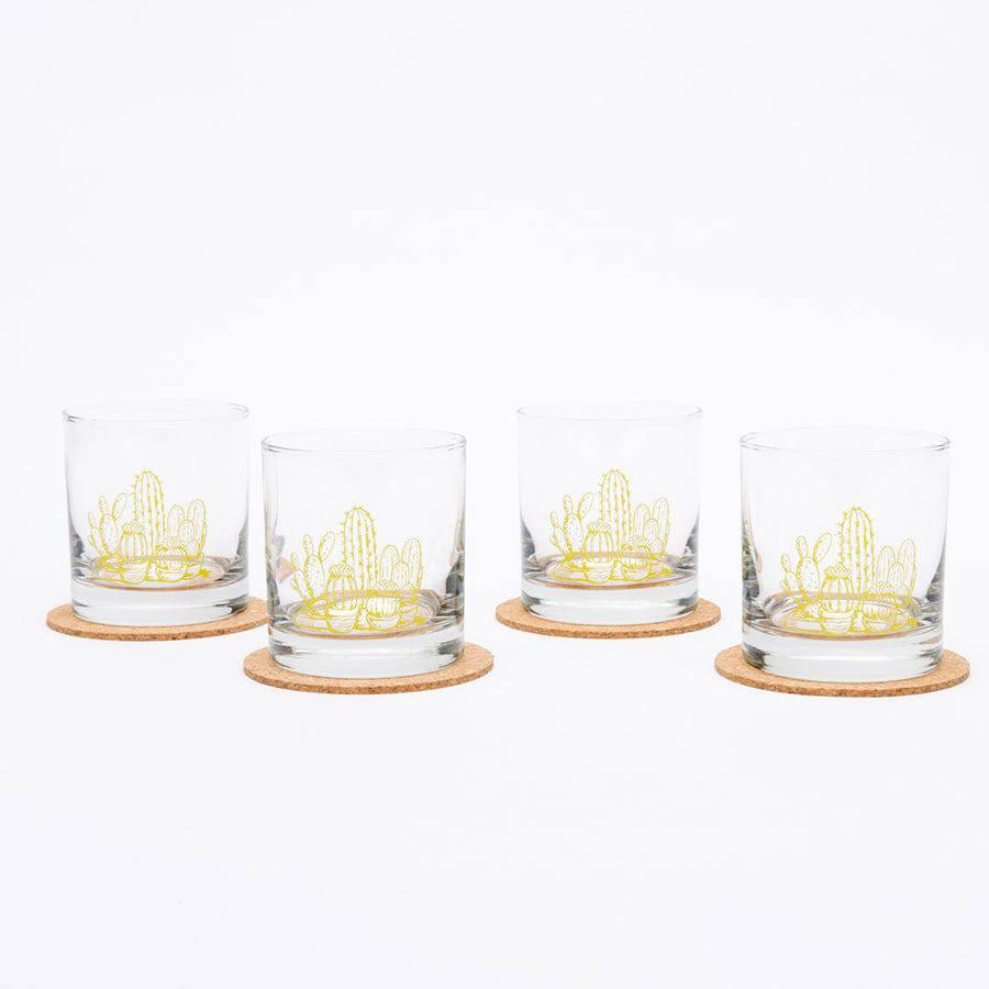 Set of four whiskey glasses with yellow cactus design on cork coasters, white background
