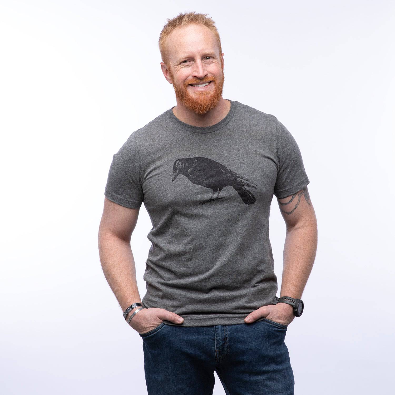 Man wearing a gray graphic t-shirt with a black crow illustration, casual style