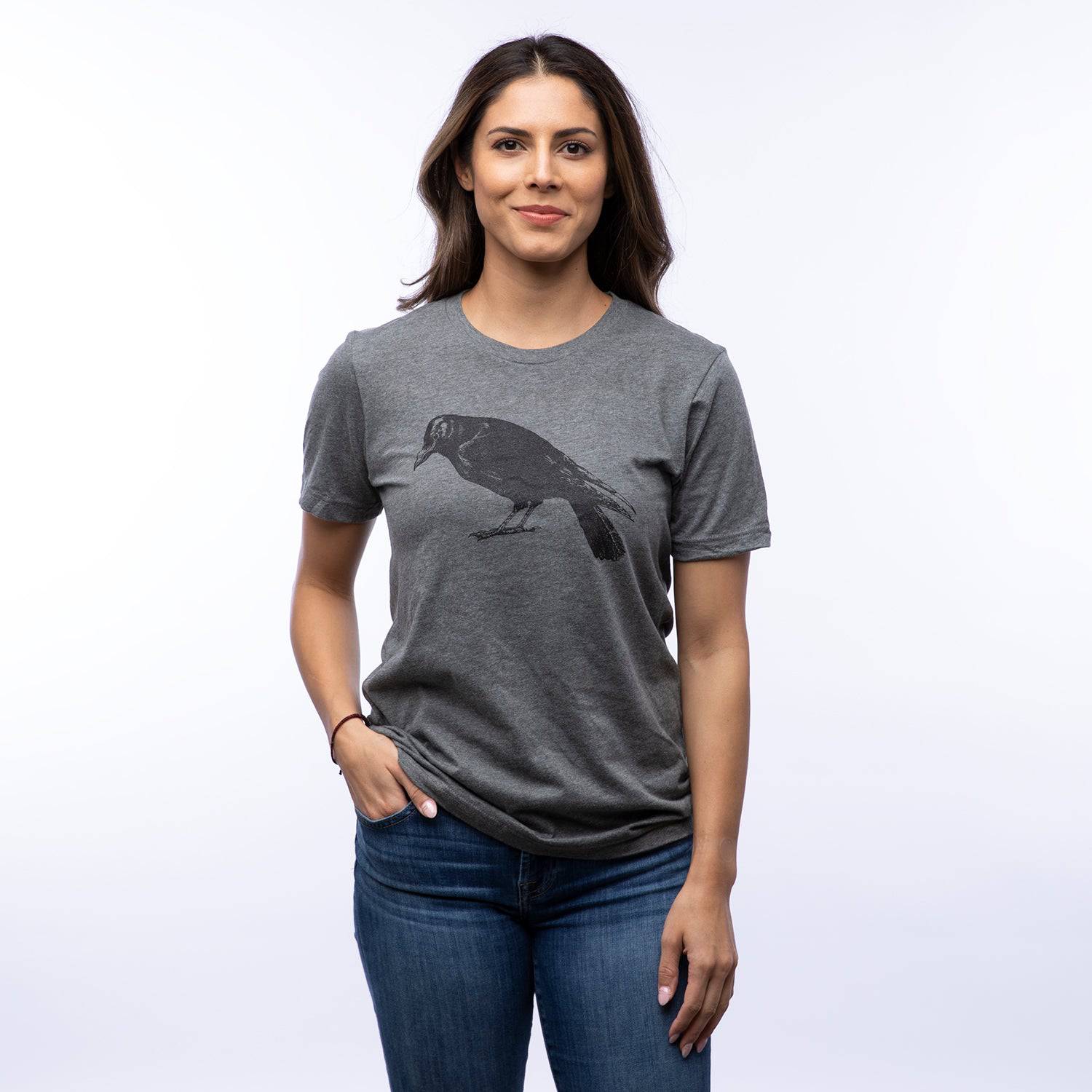 Woman wearing a gray unisex t-shirt with a black crow graphic illustration on front