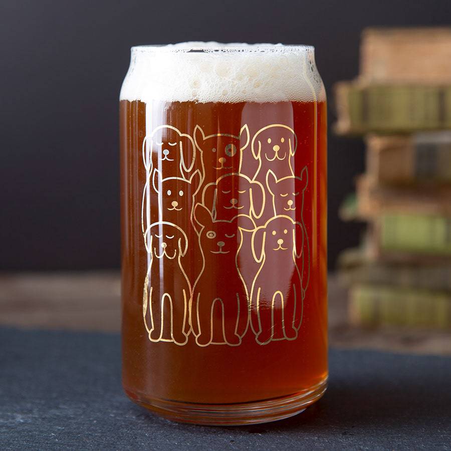 Beer can glass with cute gold dog illustrations, filled with amber beer on table