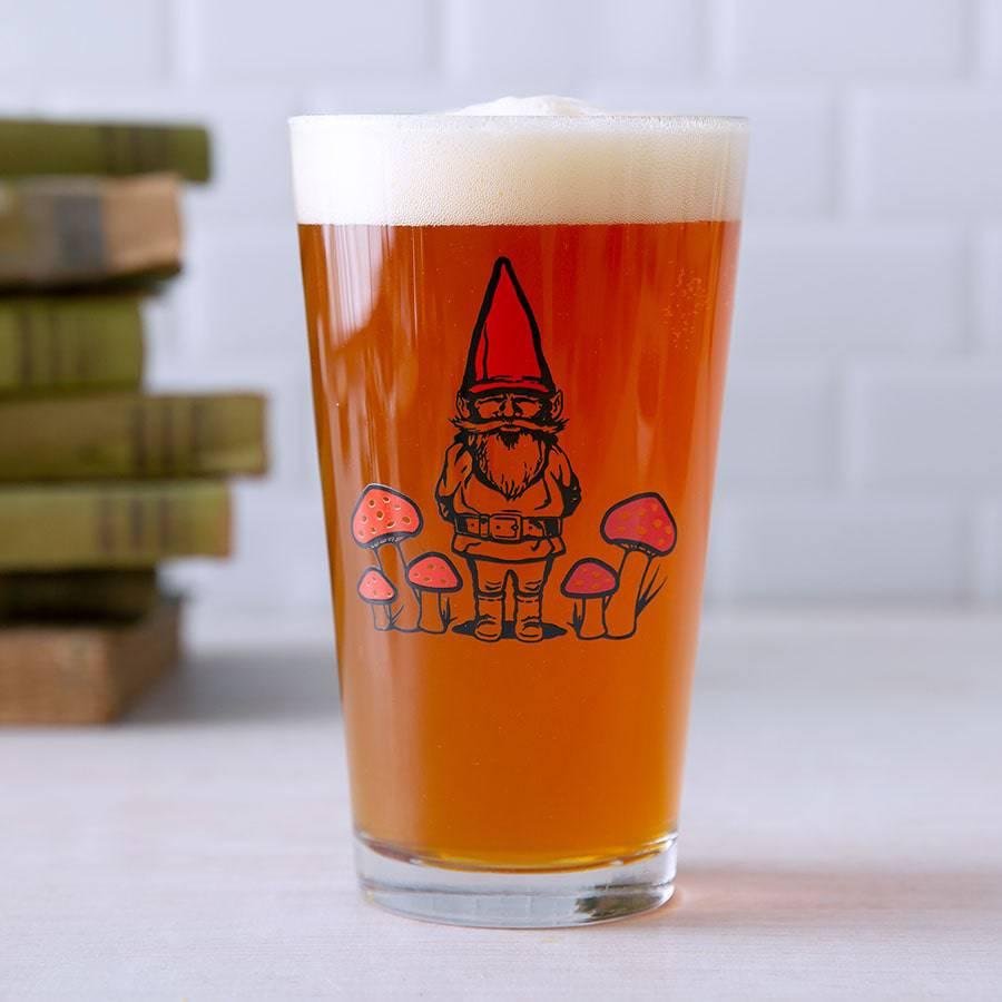Pint glass of beer with a gnome and mushroom illustration, whimsical barware design