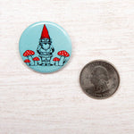 Round button with gnome and red mushrooms, shown next to a US quarter for size reference.