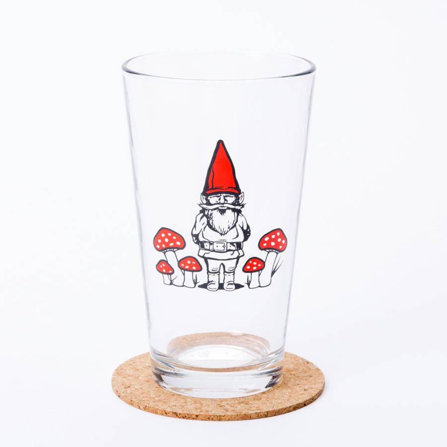 Pint glass with gnome and red mushroom illustration, whimsical barware on cork coaster