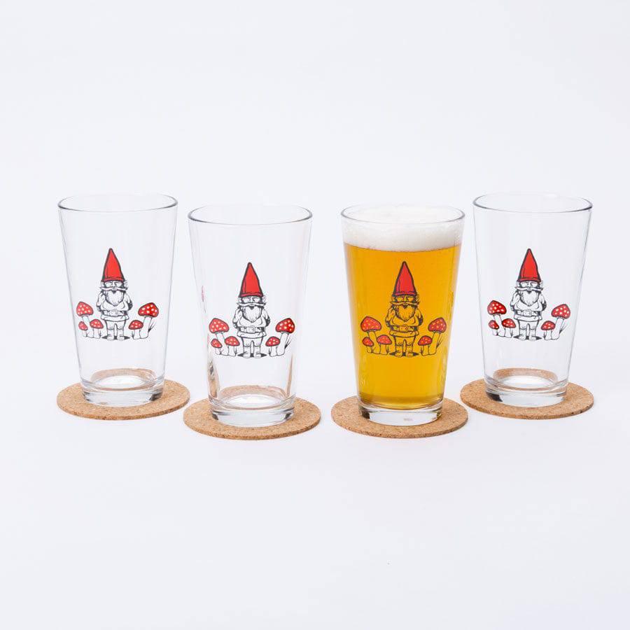 Set of four pint glasses with gnome and mushroom illustrations, one filled with beer