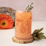Iced orange drink in mushroom can glass with wood coaster, flower, and succulent accents