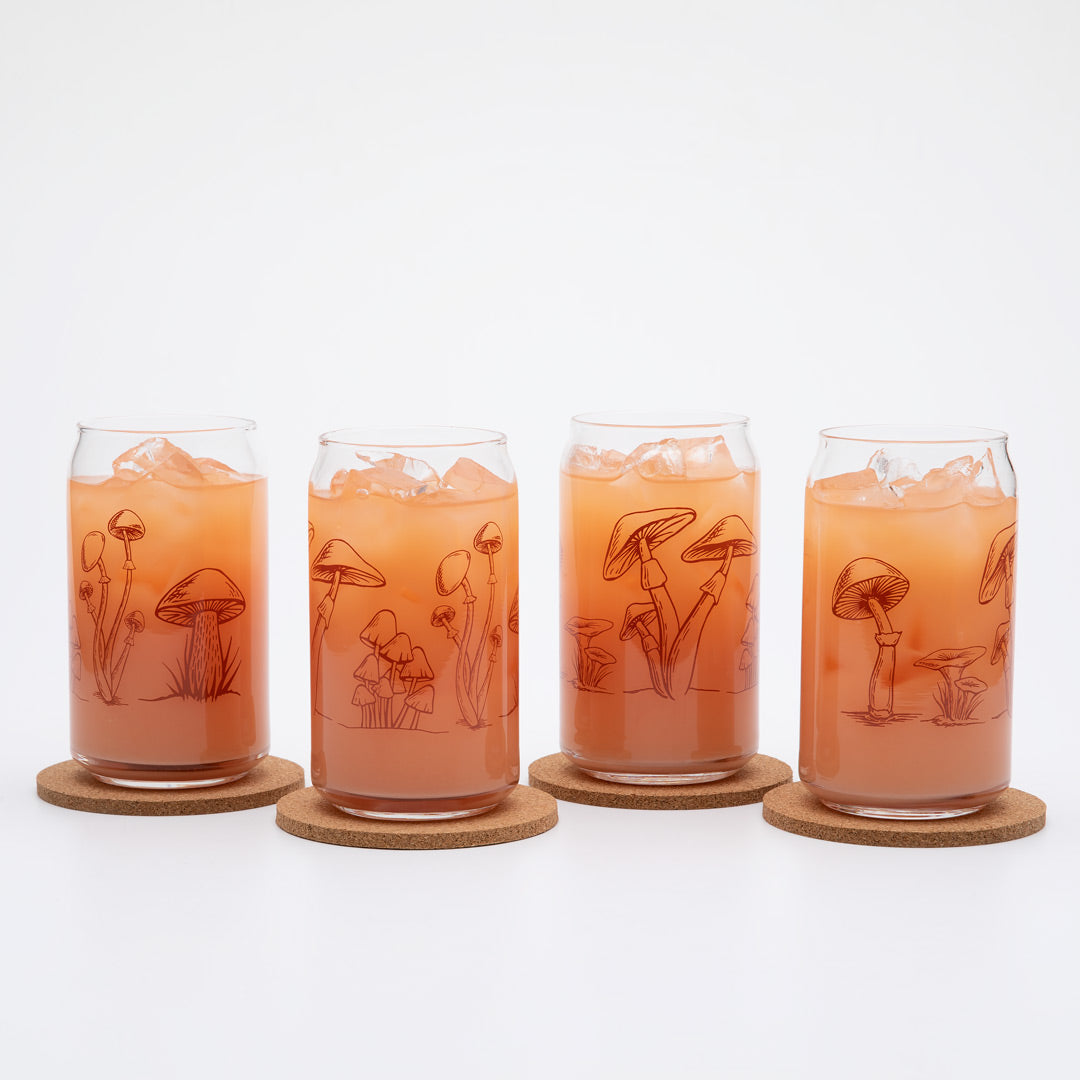 Set of four can-shaped glasses with etched mushroom designs, filled with iced drinks