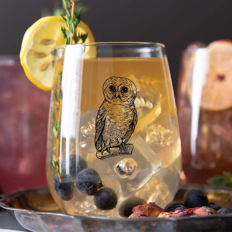 Owl stemless wine glass with iced cocktail, blueberries, and lemon garnish