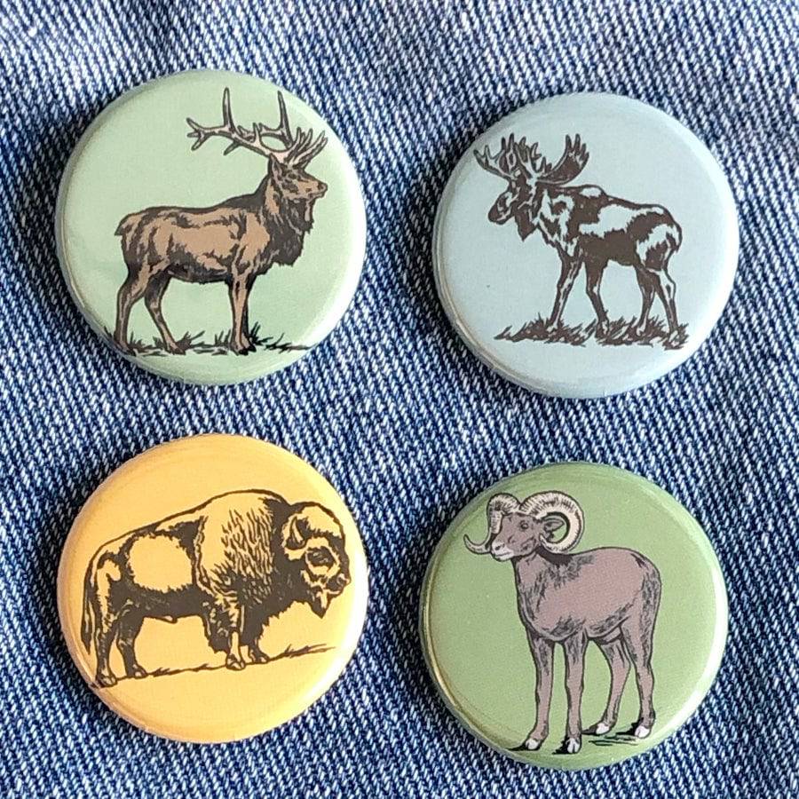 Set of four animal buttons with elk, moose, bison, and ram designs on denim fabric