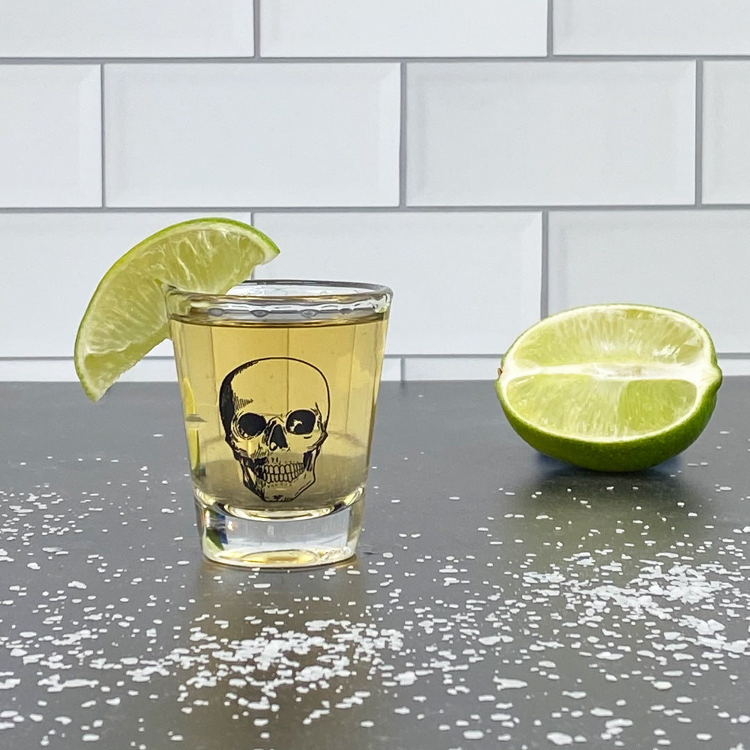 Skull shot glass with tequila and lime wedge, salt on counter, modern barware