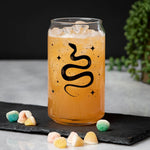 Snake can glass with iced orange drink, black snake graphic, candy, and plant decor