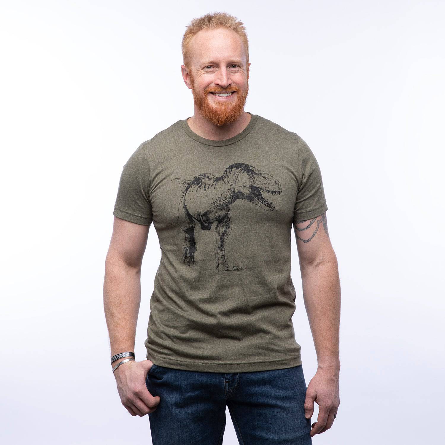 Man wearing olive green T-shirt with black T-Rex dinosaur graphic, casual style