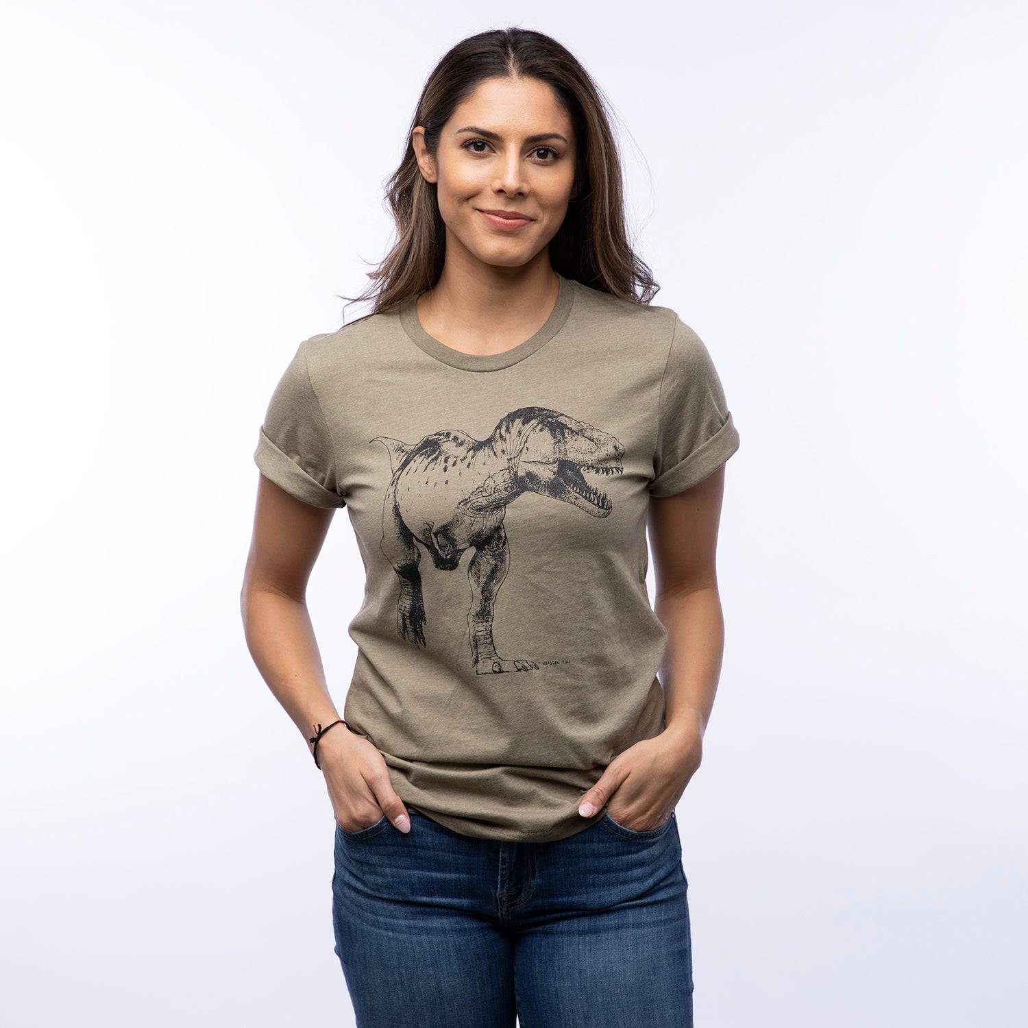 Woman wearing khaki graphic T-shirt with black T-Rex dinosaur illustration, casual style