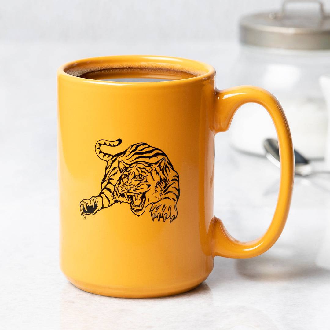 Yellow ceramic coffee mug with black tiger illustration on a kitchen counter