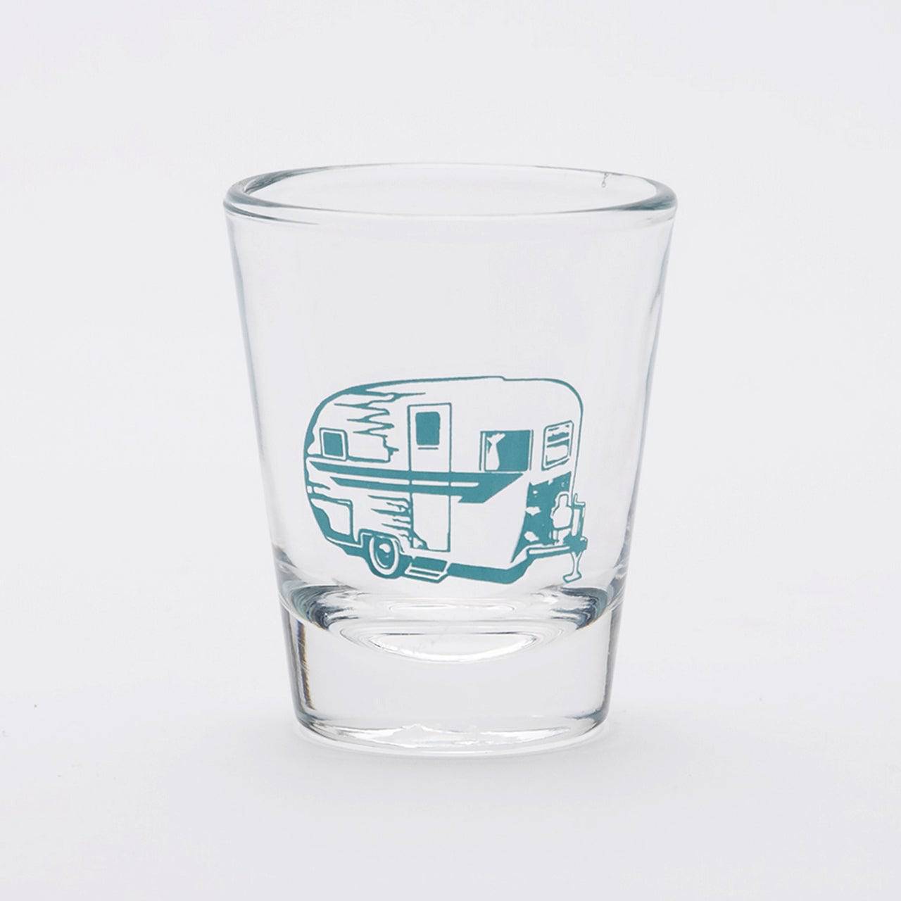 Clear shot glass with blue vintage camper trailer graphic on white background